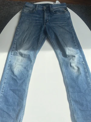 Blå replay jeans - Snygga blå jeans från Replay med klassisk femficksmodell och raka ben. Jeansen har en tvättad look med ljusare partier och detaljerade sömmar. Perfekta för en avslappnad stil och passar till det mesta.