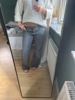 Gråa raka jeans med låg midja - Säljer ett par gråa jeans med låg midja och raka ben. Jeansen har klassisk femficksdesign och är tillverkade i denim. Perfekta för en avslappnad och trendig look. Obs jag har klippt längst ner på jeansen (är 164)