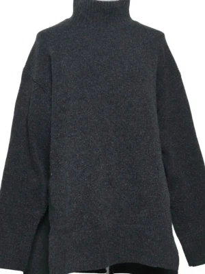 Mörkgrå stickad polotröja - Mysig mörkgrå stickad polotröja med hög krage och avslappnad passform. Tröjan har långa ärmar och är tillverkad i ett mjukt, värmande material. Perfekt för lager-på-lager och en chill look.