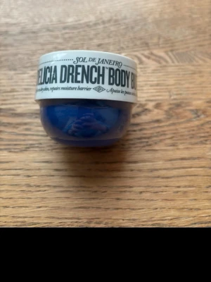 Sol de Janeiro Delicia Drench Body Butter - Delicia Drench Body Butter från Sol de Janeiro i en blå rund burk med vit lock. Innehåller Cheirosa 59-doft, prebiotisk hibiskus och brasilianskt lugnande komplex. Perfekt för dig som vill ha extra återfuktning och en lyxig känsla.