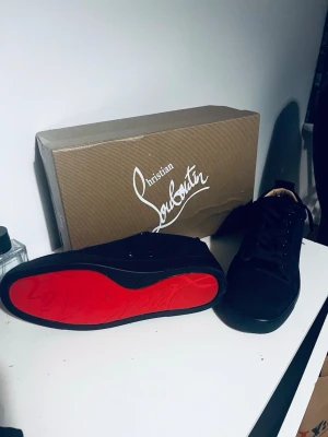 CL blåa skor - Navy sneakers från CL med ikonisk röd sula. Skorna har en klassisk låg siluett, snörning framtill och är tillverkade i ett material som ser ut som mocka eller nubuck. Perfekta för dig som vill sticka ut med exklusiv stil. Använd kanske 4 gånger skriv om ni har några funderingar