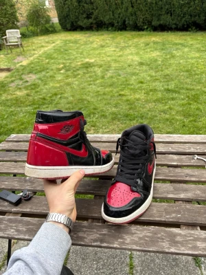 Air Jordan 1 Retro High OG Patent Bred - storlek 44 inte använda för mycket Riktigt fint skick utöver lite heel drag men inget som syns eller påverkar funktion. inga repor och allt glans är som det ska.