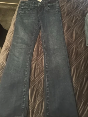 Mörkblå bootcut jeans - Snygga mörkblå bootcut jeans med klassisk femficksdesign och lätt tvättad look. Jeansen har normal midja och utsvängda ben, perfekta för en trendig och avslappnad stil. Tillverkade i stretchigt denim för extra komfort.