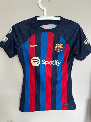 FC Barcelona matchtröja Rolfö #16 - Snygg FC Barcelona hemmatröja 2022/2023 med Rolfö #16 på ryggen. Köpt från officiella barça store. Tröjan har blå och röda vertikala ränder, klubbmärke och Nike-logga på bröstet samt Spotify som sponsor. Tillverkad i lätt och ventilerande material, perfekt för fotboll eller träning. Defekt, trycket på ryggen har lossnat lite.