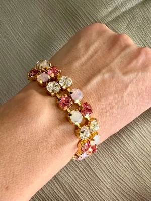 Armband - rosa/vitt - Armband i rosa toner samt vitt. Justerbart från ca 16 cm. Guldfärgad kedja.