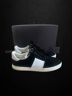 Helt nya! Valentino flycrews. - Snygga sneakers från Valentino i svart mocka och vitt läder med vita detaljer och svart snörning. Klassisk låg modell med vit sula och diskreta nitar baktill. Perfekta för dig som gillar stilrena och exklusiva skor.