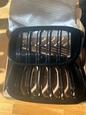 Svarta njurgrillar till BMW - Säljer ett par svarta njurgrillar till BMW. Grillarna är tillverkade i plast och har en blank finish med klassisk vertikal design. Perfekt för dig som vill ge bilen ett sportigare utseende. Levereras i originalkartong.