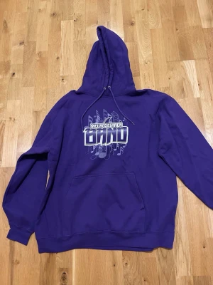 Lila hoodie Melrose Area Band stl XXL bra skick - Snygg lila hoodie med tryck från Melrose Area Band på bröstet och coola noter i bakgrunden. Klassisk känguruficka och huva med snörning. Perfekt för dig som gillar musik och vill sticka ut med en färgstark stil.