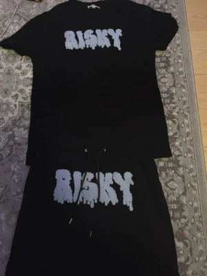 Risky shorts och T-shirts  - Säljer ett svart set med t-shirt och shorts, båda med stort vitt tryck 'RISKY' på bröstet och benet. Setet har en avslappnad passform och shorts med dragsko i midjan. Perfekt för en cool och bekväm stil. Säljs ej längre 
