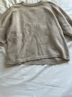 Beige stickad tröja - Mysig beige stickad tröja med avslappnad passform och rund halsringning. Tröjan har ribbade muddar vid ärmslut och nederkant, perfekt för lager-på-lager och chill dagar.