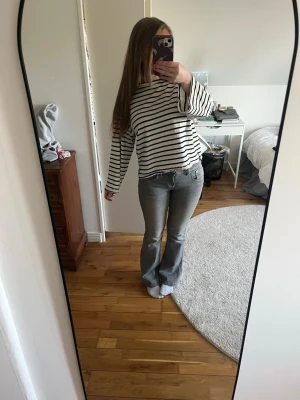 Grå bootcut jeans från Gina - Snygga grå jeans från Gina med bootcut-modell och klassisk femficksdesign. Jeansen har en lätt tvättad look och är tillverkade i ett mjukt denimtyg som sitter skönt. Perfekta för dig som gillar en avslappnad men trendig stil.