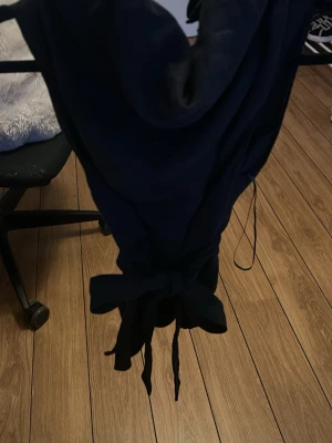 Mörkblå baddräkt med knytband - Snygg mörkblå baddräkt med djup urringning och knytband i midjan. Klassisk modell med feminina detaljer och stilren look. Perfekt för stranden eller poolen. Materialet är stretchigt och följsamt för en bekväm passform.