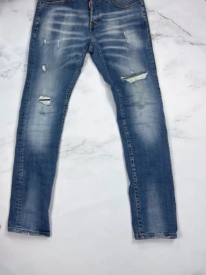 Blå Dsquared2 Jeans Slim fit  - Snygga blå jeans från Dsquared2 med slitningar och trasiga detaljer på benen. Jeansen har en slim fit passform, klassisk  och tydliga ljusa tvättade partier. Perfekta för en trendig och avslappnad stil.