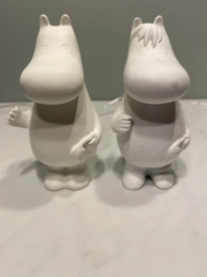 Vita Muminfigurer i keramik - Två vita Muminfigurer i keramik, stilrena och detaljrika med rund form och klassiskt utseende. Perfekta som dekoration eller samlarobjekt för Mumin-fans. Figurerna är ca 20 cm höga och har en matt yta.
