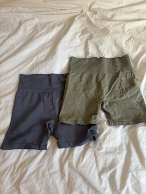 4 högmidjade tränings shorts - 4 högmidjade tränings shorts i ribbad stil, ett par i mörkblå, ett par i rosa, ett par i grå och ett par i olivgrönt. Alla är stretchiga och har bred linning för extra komfort. Perfekta för träning eller avslappnade dagar.