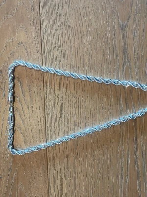 Tjockt silverhalsband i repkedja - Säljer ett snyggt halsband i äkta 925 sterling silver med repkedja. Halsbandet har en vriden design som ger en cool och modern look. Perfekt för dig som gillar stilrena och tidlösa accessoarer. Lås med karbinhake.
