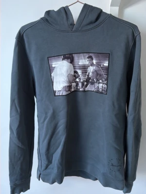 Grå hoodie med boxningsmotiv - Limitato hoodie med Muhammed Ali köpt på zagander, som såldes i begränsat upplaga hoodien är aldrig använd och kommer med sin original box och certifikat som visar att det är hoodie nummer 6/500 tillverkare. Nypris:2995:-