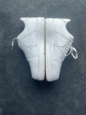 Nike Air Force 1 vita sneakers - Kan diskutera pris.                                  Klassiska helvita Nike Air Force 1 sneakers i läder med ikonisk swoosh på sidorna och tjock sula. Perfekta för dig som gillar en clean och tidlös look. Skorna har lågt skaft och snörning framtill.     Har ingen box!! Nästan aldrig använda