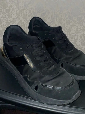Svarta Michael Kors sneakers med gulddetalj - Nyskick ÄKTA Michael Kors skor i storlek 36,5. 