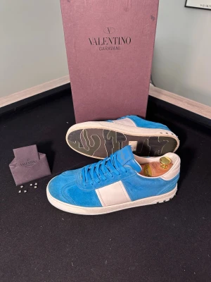 Valentino Garavani Flycrew – Ljusblå Mocka - Säljer nu ett par sjukt feta Valentino Garavani Flycrew i en unik Ljusblå Mocka som sticker ut enormt mycket nu inför våren och sommaren. Skicket är ruggigt bra som ni ser på bilderna, alla nitar är kvar och mockan är i fint skick. Storleken är 42 men passar även 43. Nypriset ligger runt 7500kr. Det är ett Fullset där Box, Valentino Kuvert och Extra nitar ingår. Har ni några funderingar är det bara att höra av sig, priset kan diskuteras vid snabb affär😁🤝 