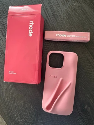 Rhode mobilskal iphone 15 max pro - Helt ny oanvänd rhode mobilskal med tillhörande läppglans i färgen "Ribbon", passar Iphone 15 max pro. Fått i present kan ej garantera äktheten.