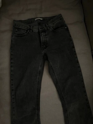 mörkgrå low waist jeans  - Snygga mörkgrå low waist jeans med bootcut jeans ben dom är lite slitna ner till som de syns på bilden annars i väldigt bra skick 