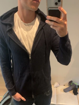 Mörkblå cashmere hoodie John Henric - Snygg mörkblå hoodie från John Henric i lyxig cashmere. Dragkedja framtill, två fickor och klassisk huva. Perfekt för dig som vill ha en mjuk och stilren hoodie med premiumkänsla. Passar till jeans och shorts. Nypris 2999kr
