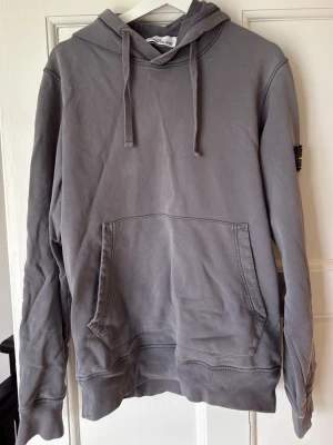 Grå hoodie från Stone Island - Säljer en grå hoodie från Stone Island. Finns tecken på slitage, se bild. Det är inget mer än det. 