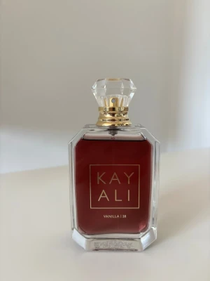 Kayali Vanilla | 28 Eau de Parfum - Kayali Vanilla | 28 är en lyxig parfym med varm vaniljdoft. Flaskan är fyrkantig med klara kanter, djupt bärnstensfärgat innehåll och elegant guldtext. Locket är kristalliknande och detaljerna i guld ger en exklusiv känsla. Perfekt för dig som älskar söta och mjuka dofter.