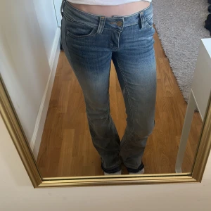 Blå bootcut jeans  - Säljer ett par blå bootcut jeans från cheap monday med lätt slitna detaljer vid fötterna och klassisk femficksmodell. Jeansen har en något utsvängd passform nedtill och normalhög midja. Perfekta för en avslappnad och trendig look.