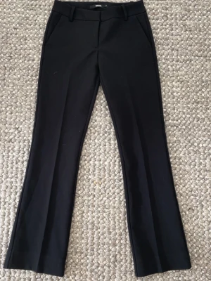 Svarta kostymbyxor  från bikbok - Svarta low waist kostymbyxor med utsvängda ben. De är i storlek 32. Använd ca 1 gång. Perfekt  för en dressad look och passar till många olika outfits