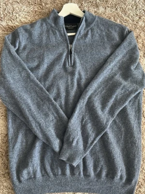 Halfzip - Blå cashmere tröja från Mi & Cashmere med halv dragkedja och hög krage. Tillverkad i mjuk cashmere som känns lyxig mot huden. Perfekt för lager på lager och har ribbade muddar vid ärmslut och nederkant.