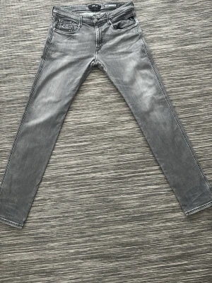 Grå slim fit jeans från Jack & Jones - Snygga grå slim fit jeans från replay med klassisk femficksdesign och diskreta slitningar. Jeansen har raka ben och är tillverkade i stretchig denim för en bekväm passform. Perfekta för en trendig och avslappnad stil.