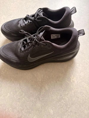 Svarta Nike Zoom sneakers löpar skor  - Säljer ett par svarta Nike Zoom sneakers med låg profil. Skorna har en stilren design med mesh-överdel för bra ventilation, klassisk Nike Swoosh på sidan och snörning. Mellansulan är rejält dämpad för extra komfort och yttersulan är slitstark.