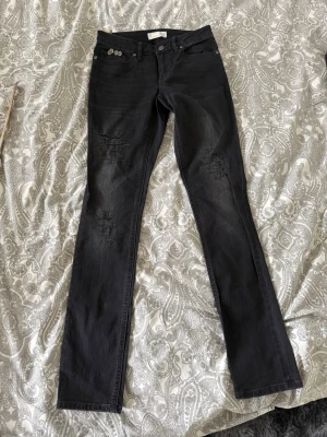 Svarta jeans från Odd Molly - Snygga svarta jeans från Odd Molly med raka ben och diskreta slitningar på låren. Jeansen har klassisk femficksmodell och coola detaljer på knapparna. Perfekta för en trendig och avslappnad stil.
