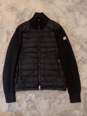 Moncler tricot cardigan Stl S passar Xs - Säljer en moncler tricot cardigan som är köpt på merch Sweden, jag har orderbekräftelse och en returfraktsedel(se bild 7 för retur sedeln). Bara att fråga för bild på orderbekräftelse. Cardiganen är i Stl S men sitter som en xs. Skulle säga att den passar någon som är från 162-175 typ. Kan nog vara från 160-180. Cardiganen har 1/2 lagade hål(se bild 4). Den har också ett litet hål på armbågen(se bild 6). Cardiganen har också ett litet märke längst ut på armen men annars är den i bra skick. 