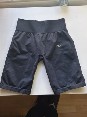 Svarta träningsshorts från ICANIWILL - Svarta shorts från ICANIWILL med hög midja och ribbad linning. Perfekta för träning, tillverkade i ett stretchigt material som ger bra rörelsefrihet. Diskret logga på ena benet och längre benlängd för extra komfort.