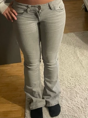Ljusgrå bootcut jeans - Säljer ett par ljusgrå bootcut jeans och låg midja. Bra skick men en av bälteshållarna bak på byxorna sitter lite löst. Storlek xs och sitter ganska tajt💕