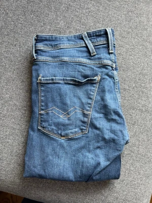 Blå jeans från Replay - Snygga blå jeans från Replay med klassisk femficksdesign och ljus kontrastsöm. Jeansen har en normal passform och är tillverkade i denim med en lätt tvättad look. Perfekta för dig som gillar stilrena och tidlösa jeans.