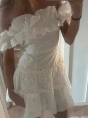  Ny trendig student Vit offshoulder klänning med volang - Superfin vit kortklänning med offshoulder och volangdetaljer. Klänningen har broderade spetsmönster och är tillverkad i bomull, perfekt för sommarens alla tillfällen. Söt och trendig modell med romantisk känsla. Ny med prislapp 