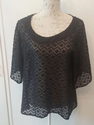 Svart transparent blus med mönster - Säljer en svart transparent blus med geometriskt mönster och halvtransparent tyg. Blusen har rund halsringning och trekvartsärm.