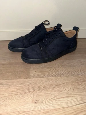 Mörkblå sneakers med röd sula - Snygga mörkblå sneakers med ovandel i mocka och klassisk snörning. Skorna har en unik röd sula och diskreta detaljer. Perfekta för dig som gillar stilrena och trendiga skor med en twist.