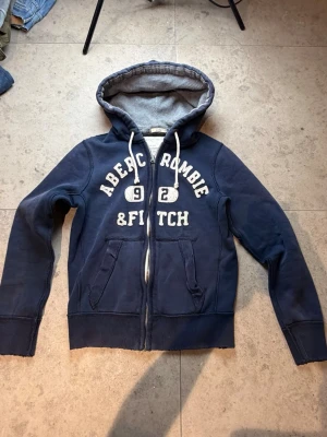 Abercrombie fitch zip hoddie  - Superfint skick utöver ett litet hål vid armbågen som ej syns. Finns bild på bild 3. Tveka inte på att ställa frågor
