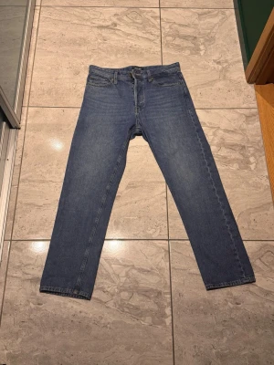 Blå jeans från Jack and Jones  - Säljer ett par blå jeans från Jack and Jones. Jeansen har normal midja och stängs med knappar.  Perfekta för en avslappnad och stilren look.