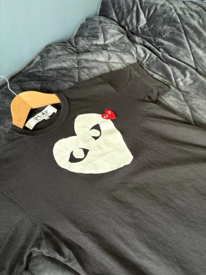 Svart Comme des Garçons PLAY t-shirt - Svart t-shirt från Comme des Garçons PLAY med stort vitt hjärta och ögon på bröstet samt ett litet rött hjärta. Köpt från farfetch