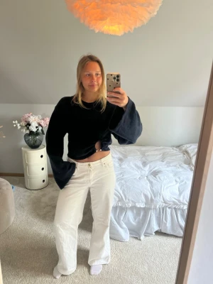 Svart croppad tröja med vida ärmar - Svart croppad topp med vida, långa ärmar och en snygg cut-out detalj framtill. Mjuk och skön, perfekt för dig som gillar en trendig och avslappnad stil. Passar till både jeans och kjol.