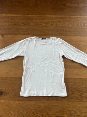 Vit långärmad topp från brandy Melville - En enkel och stilren vit långärmad topp från brandy. Toppen har rund halsringning och är gjord i ett mjukt material som känns skönt mot huden. Perfekt att matcha med jeans eller kjol för en clean look.