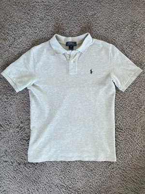 Ljusgrå pikétröja från Polo Ralph Lauren - Klassisk ljusgrå pikétröja från Polo Ralph Lauren . Tröjan är i fint skick och är i storlek 10-12. Hör av dig direkt vid frågor eller funderingar!😄