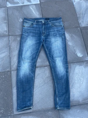 Tiger of sweden jeans  - Halloj!!! Dessa sjukt Snygga blå slim fit jeans med ljusa sjuka fades och små slitningar på låren och knäna. Klassisk design med dragkedja och knapp i midjan. Jeansen har en modern tvätt och raka ben, perfekta till en avslappnad stil. Sjukt feta fades otroligt snyggt faktiskt!!! Storlek 34/30 skick 9,5/10 modell evolve🕺hör av dig vid mer frågor eller funderingar🤩mvh Ga