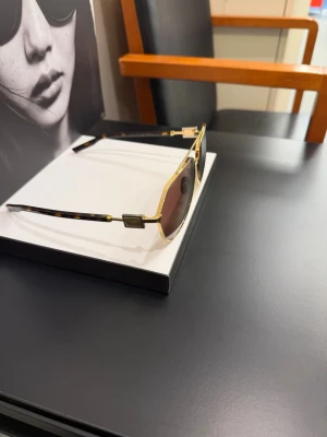 Dolce&Gabbana guldiga pilotbågar - Snygga solglasögon från Dolce&Gabbana med klassisk pilotform. Bågarna är i guldigt metall och har bruna glas. Skalmarna har ett sköldpaddsmönster som ger en extra touch. Perfekta för dig som vill ha en tidlös och trendig look.